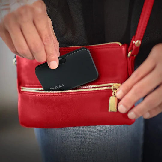 ThinOptics najtanjša bralna očala z Universal Pod etuijem za v torbico – zamegljena oseba daje očala v žensko torbico